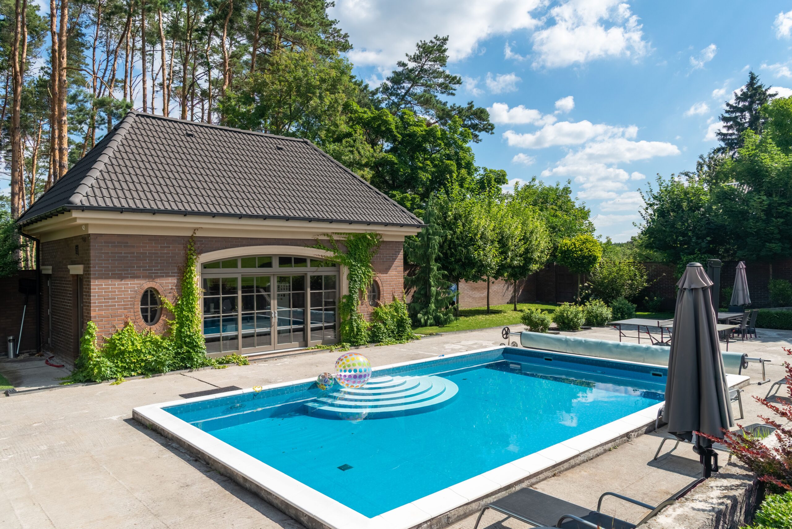 Terrasse couverte avec vue sur piscine, espace pool house aménagé